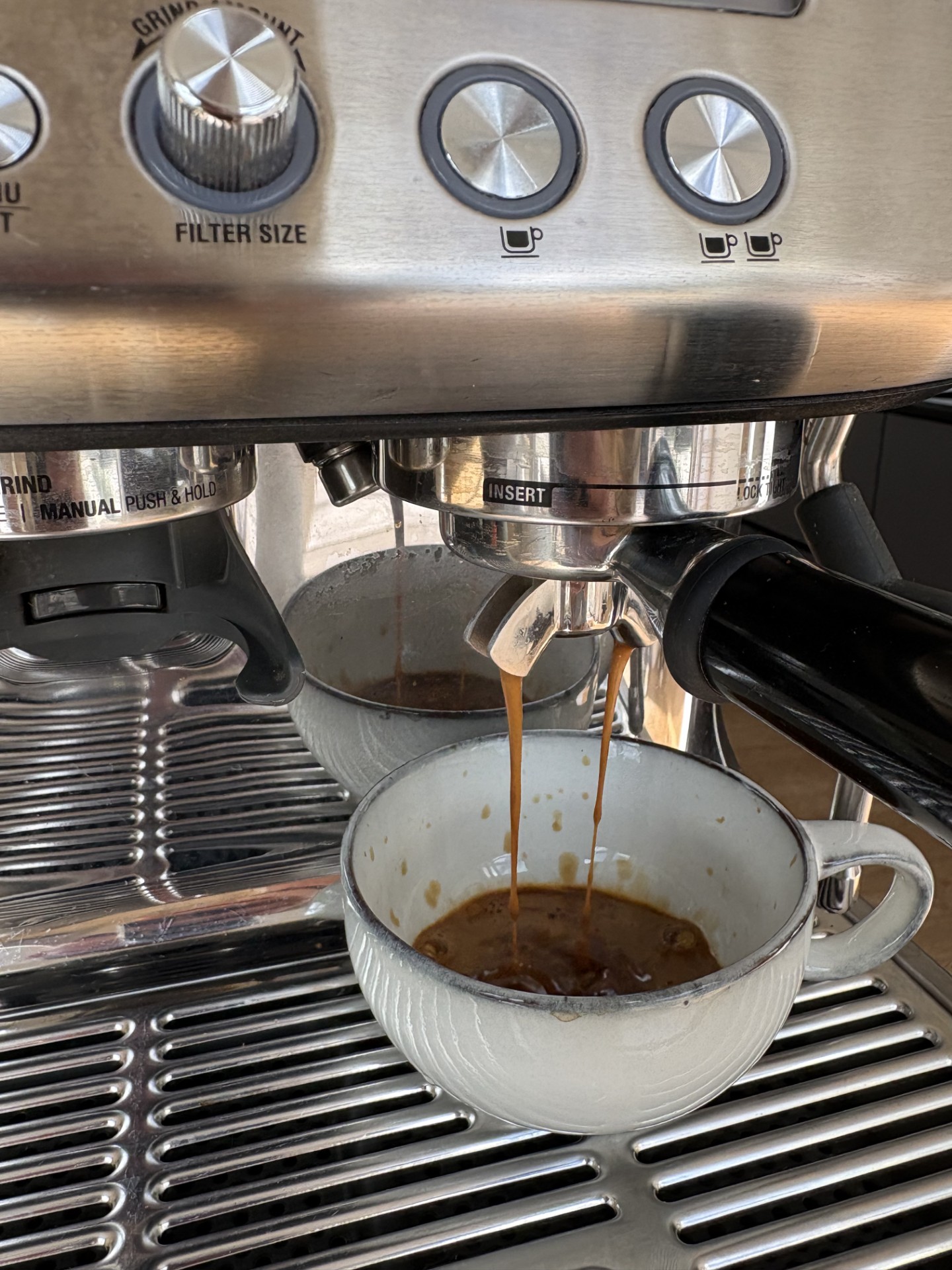 Espresso der løber fra dobbelt tud ned i en keramisk kop under funktionstest
